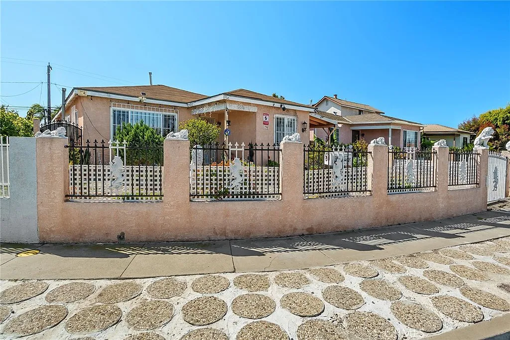 Single-story house with stone fence and a tiled roof, in California